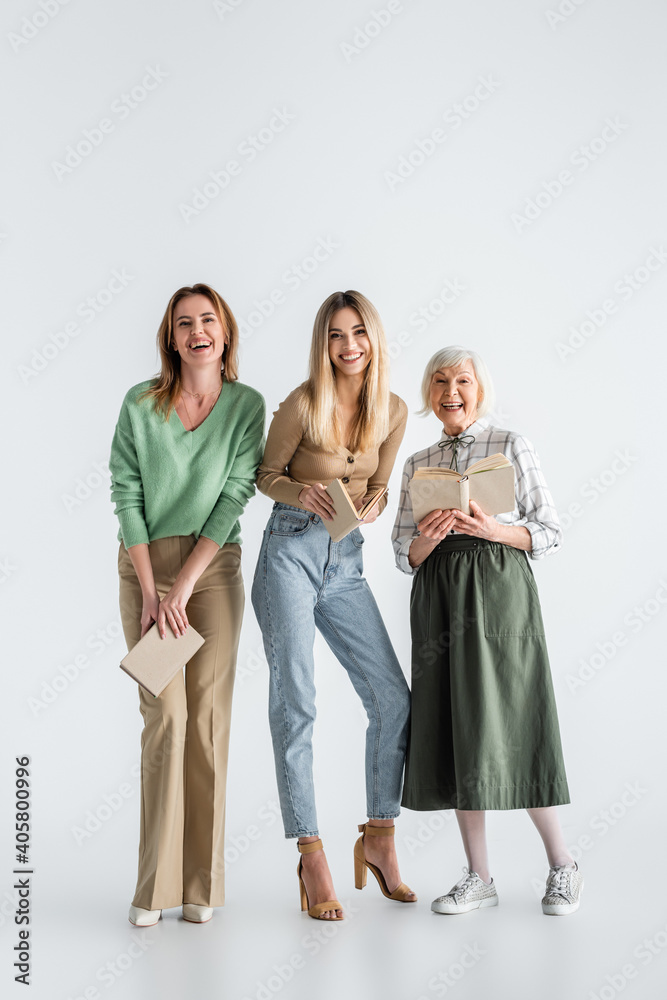 Wall mural full length of three generation of happy women holding books on white