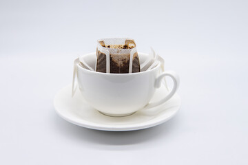 Drip or brewed coffee in white cup on white backdrop. Paper dripping bag on a cup