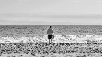 Athletic young man walking on a beach in Gran Canaria during Covid after a swim in Atlantic Ocean