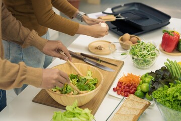 Woman and man couple family preparing vegetables to make healthy food salad in modern kitchen room