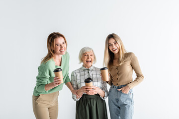 Fototapeta premium three generation of cheerful women holding paper cups isolated on white