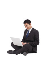 Portrait of young businessman sitting on ground,using laptop 