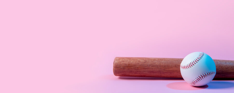 Baseball ball and bat on pink background. Team sport concept