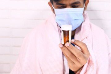 young man in surgical face mask hand holding pill container 