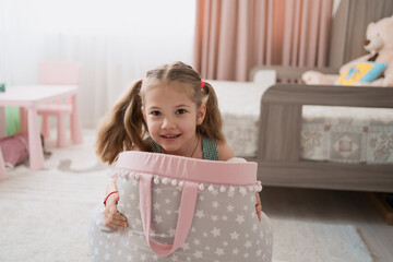 Cute little preschooler girl playing in her sunny room with a sack of toys