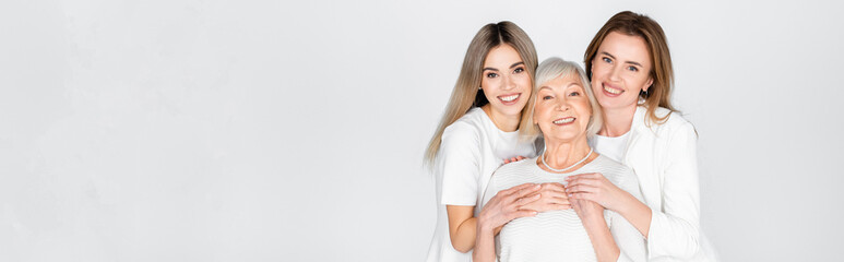 three generation of happy women smiling while looking at camera isolated on grey, banner