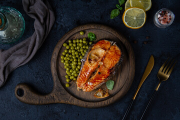 Cooked salmon steak with green peas on wooden board for serving