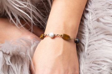 Female hand wrist wearing brass golden bracelet with various mineral stones - 405808500