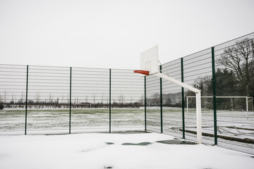 Minimalistic sport area covered in snow, high quality.  Sport fields not used in winter.  Basketbat goal covered in snow and left lonely in the winter.  Belgium flanders sports in winter.