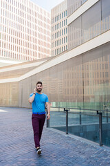 Portrait of cheerful modern businessman speaking by phone and smiling while walking outdoors