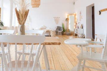 cute cozy light interior design of the apartment with a free layout of the kitchen and bedroom areas. a lot of windows, a wooden floor and a hanging swing.