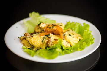 fried omelet with forest mushrooms chanterelles, on black background