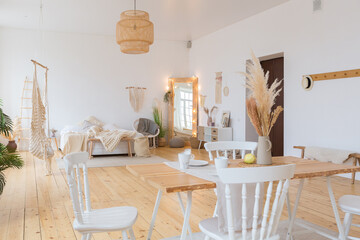 cute cozy light interior design of the apartment with a free layout of the kitchen and bedroom areas. a lot of windows, a wooden floor and a hanging swing.