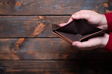 Empty wallet in hand. Male hands holding an empty wallet on a wooden background.