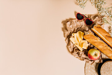 Photo of French baguette, cheese and apple arranged on paper bag
