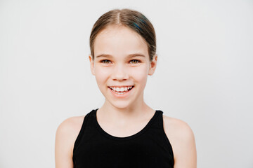 A teen girl with collected hair in a black T-shirt stands on a white background and smiles showing teeth. happy childhood. place for inscription. children's dentistry. care for health of oral cavity.