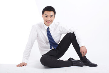 Portrait of young businessman sitting on ground