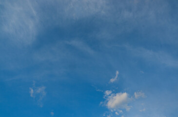 Blue deep sky with a few clouds illuminated by the setting sun.