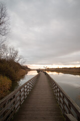 Wooden long bridge over the pond. Walking road. Autumn