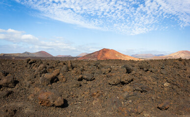 Bermeja volcano over blue sky with white clouds. Red mountain on volcanic land in Lanzarote island, Spain