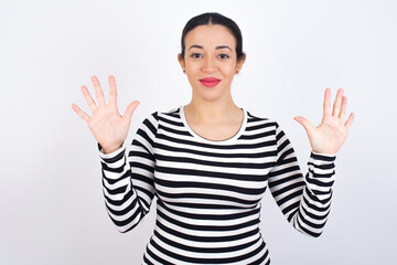 Young beautiful woman wearing stripped t-shirt against white background showing and pointing up with fingers number ten while smiling confident and happy.