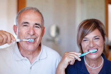 Ritratto stretto di una coppia di anziani che si lava i denti simpaticamente nel bagno di casa