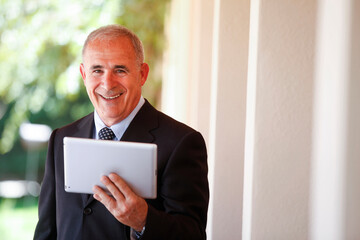 manager senior lavora tine in mano un tablet e sorride felice 