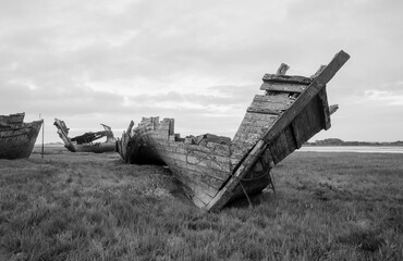Fototapeta premium An old wooden shipwreck, showing signs of decay and deterioration. An old nautical sea vessel grounded on the shore with rusty rotten ruins. Nature and the sea taking its toll on old boats.