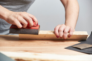 Woman fond of carpentry. Hands of a young woman sanding wood with sandpaper.