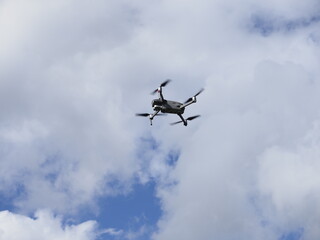 a drone flying in a blue sky with clouds