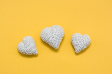 Handmade for Valentine's Day. Knitted white hearts on a yellow background