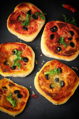 Selective focus. Appetizing mini pizzas on a dark background.
