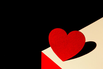 Abstract composition made of red felt heart  on bright geometric background. Valentine day concept. Love and romance theme