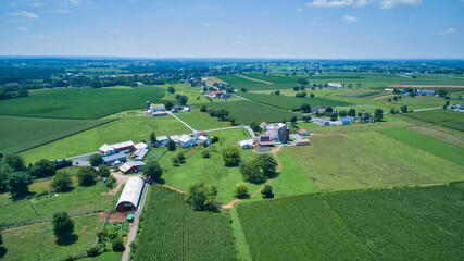 Fototapeta na wymiar Aerial View of Multiple Farms and Pastures with Field of Corn Grows on Them on a Beautiful Summer Day