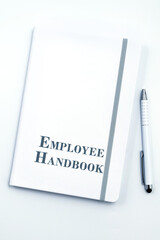 White Employee Handbook or manual with White pen on white table surface - personnel management policy, explains business goals, results, defines Leadership practices