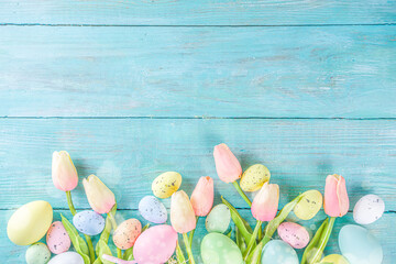 Fototapeta na wymiar Spring and Easter holiday background with tulip flowers, colorful pastel eggs on blue table top view. Happy Easter greeting card.
