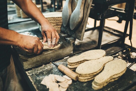 Manos trabajando en f&aacute;brica. Suelas de calzado de yute. Industria.