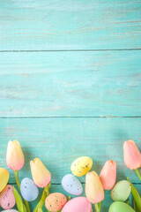 Spring and Easter holiday background with tulip flowers, colorful pastel eggs on blue table top view. Happy Easter greeting card.
