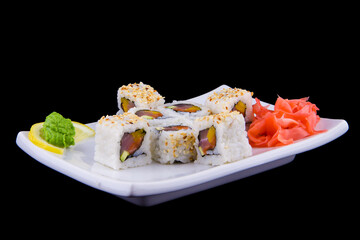 Kani avocado maki - Rolls with crab meat, avocado and sesame on a white plate on black background