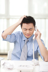 Portrait of young businessman talking on phone in office