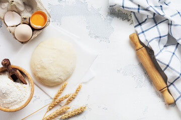 Baking background with dough and ingredients for the preparation of pasta or pancakes, eggs, flour, water and salt on white rustic old table. Top view.