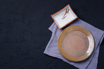 Brown ceramic plate and nipkin cloth on black table