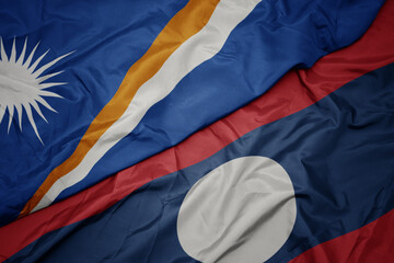 waving colorful flag of laos and national flag of Marshall Islands .