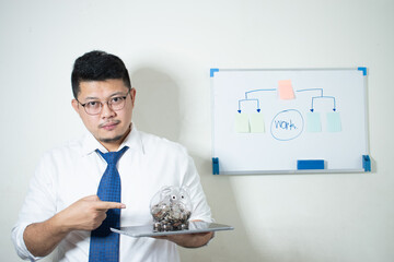 Portrait of happy successful Asian businessman holding piggy bank in hand, future investment concept