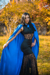 Woman in blue cloak and black dress, costumes for ladies. Girl in glamourous mascaraed dress