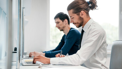 side view. smiling business man working on a laptop.