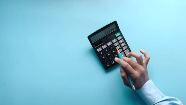 top view of man hand using calculator on blue background 
