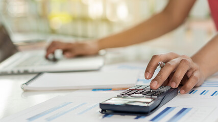 Young woman presses black calculator right hand to calculate while working in finance department in...