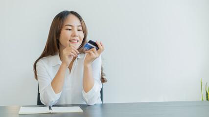 A young Asian woman holding a credit card and smiling appears to have bought something online.