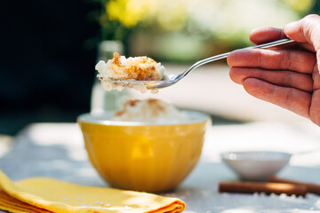 hand holding spoon with rice pudding over bowl